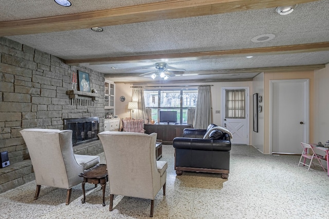 living room with beam ceiling, a textured ceiling, a fireplace, and ceiling fan