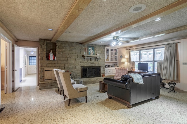 living room featuring a textured ceiling, a fireplace, and ceiling fan