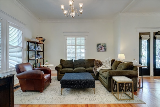 living room featuring a healthy amount of sunlight, wood-type flooring, a chandelier, and crown molding