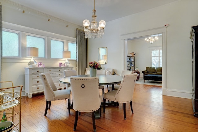 dining room with light hardwood / wood-style floors, ornamental molding, and a notable chandelier