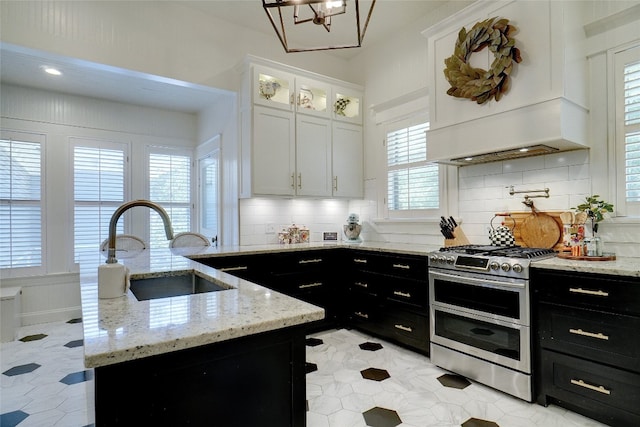 kitchen with double oven range, white cabinetry, tasteful backsplash, and light tile floors