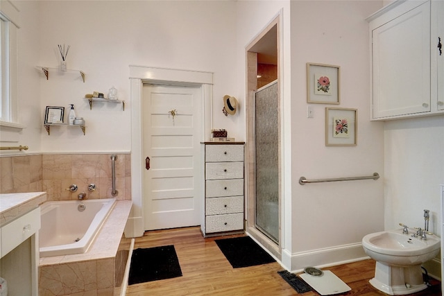 bathroom with a bidet, independent shower and bath, wood-type flooring, and vanity