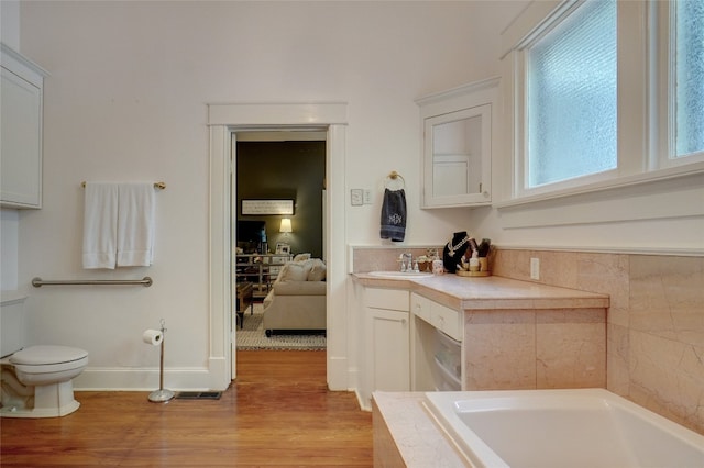 bathroom featuring hardwood / wood-style floors, vanity, toilet, and a bath to relax in