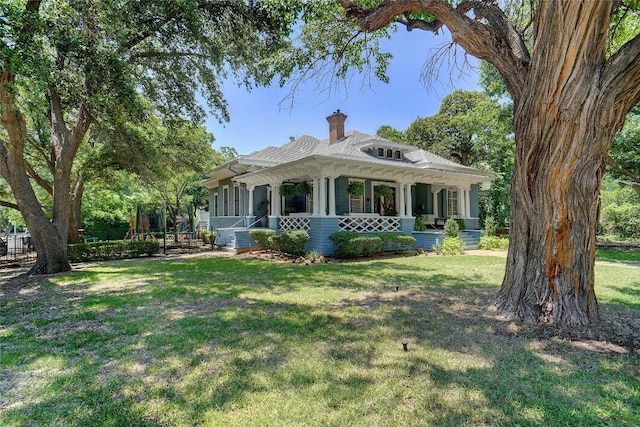 back of property with covered porch and a lawn