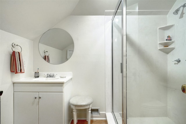 bathroom featuring vaulted ceiling, large vanity, and a shower with door