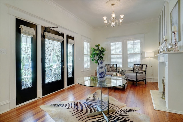 entrance foyer with an inviting chandelier, hardwood / wood-style floors, and crown molding