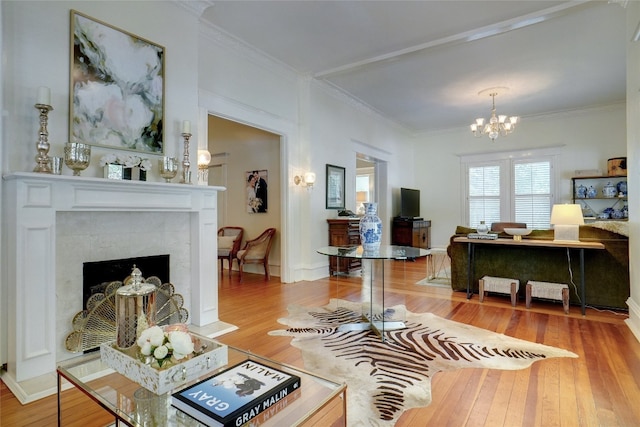 living room with ornamental molding, hardwood / wood-style flooring, a fireplace, and a chandelier