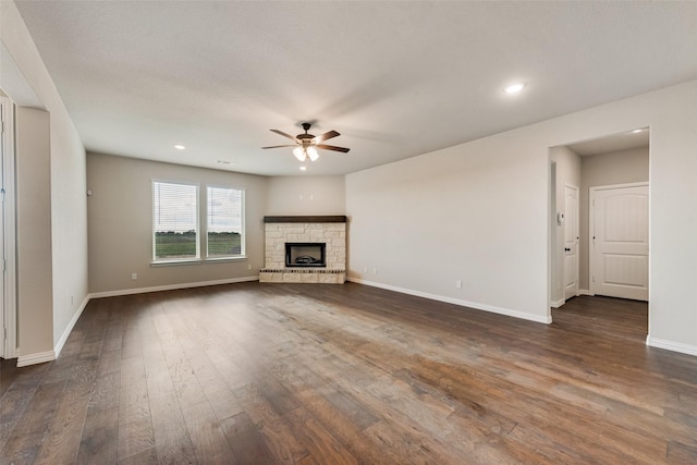 unfurnished living room featuring a ceiling fan, dark wood-style floors, recessed lighting, a fireplace, and baseboards