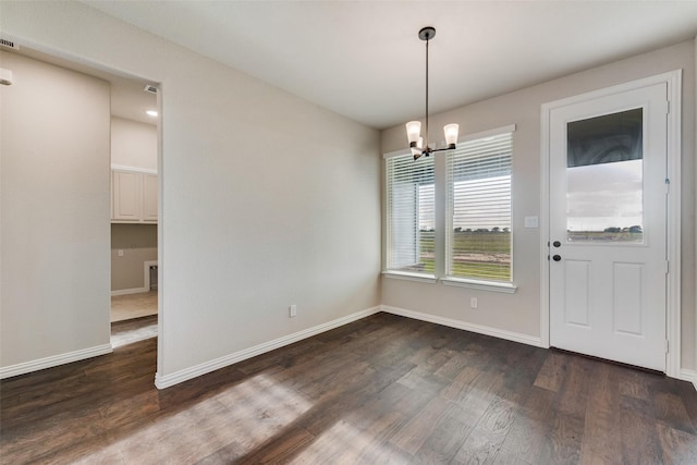 unfurnished dining area featuring dark wood-style floors, visible vents, an inviting chandelier, and baseboards