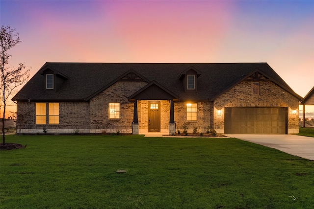 view of front facade with brick siding, driveway, an attached garage, and a front yard