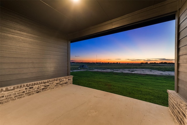 patio terrace at dusk featuring a yard