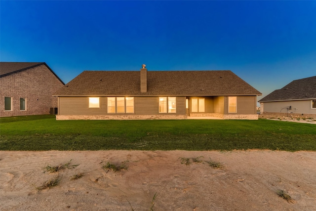 back of property with central AC unit, a lawn, and a chimney