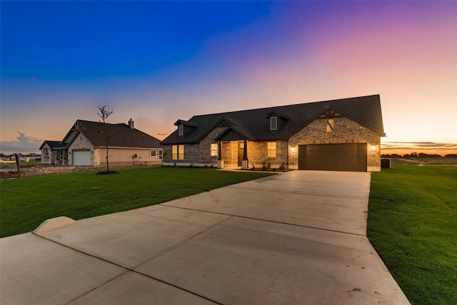 french country home with stone siding, a front lawn, an attached garage, and driveway