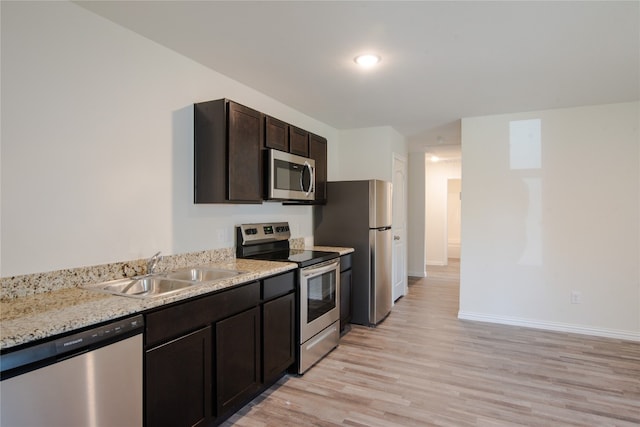 kitchen with light stone countertops, sink, light wood-type flooring, stainless steel appliances, and dark brown cabinetry