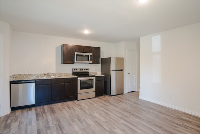 kitchen featuring sink, light hardwood / wood-style floors, stainless steel appliances, light stone countertops, and dark brown cabinetry