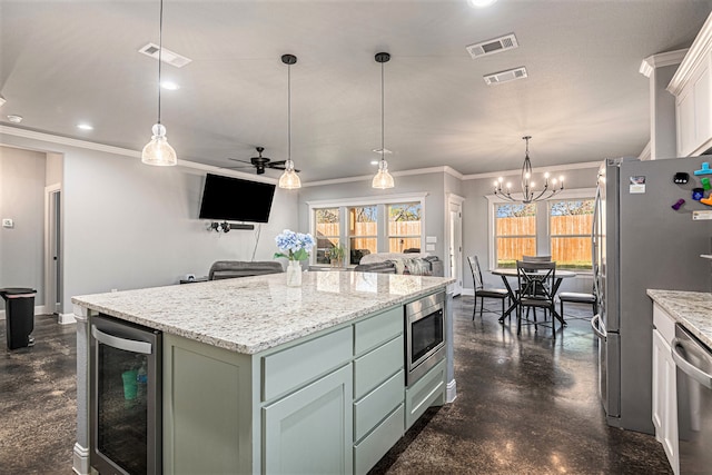 kitchen featuring wine cooler, pendant lighting, ceiling fan with notable chandelier, appliances with stainless steel finishes, and a kitchen island