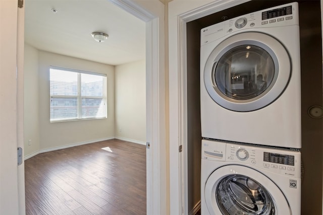 laundry area featuring stacked washer / dryer and dark wood-type flooring