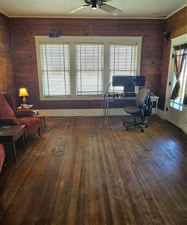 office area featuring wooden walls, ceiling fan, dark wood-type flooring, and a textured ceiling