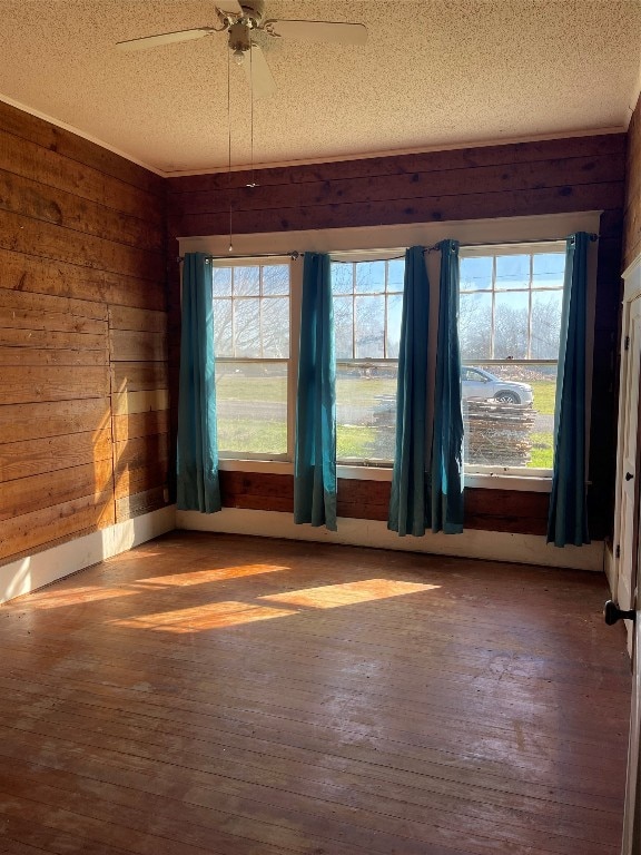 unfurnished room with wooden walls, a textured ceiling, ceiling fan, and dark hardwood / wood-style flooring