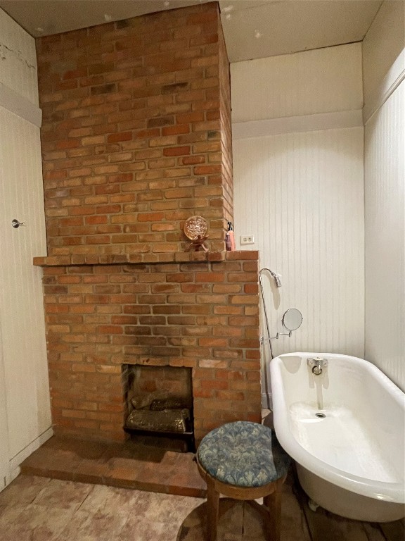 bathroom featuring tile floors, brick wall, and a washtub