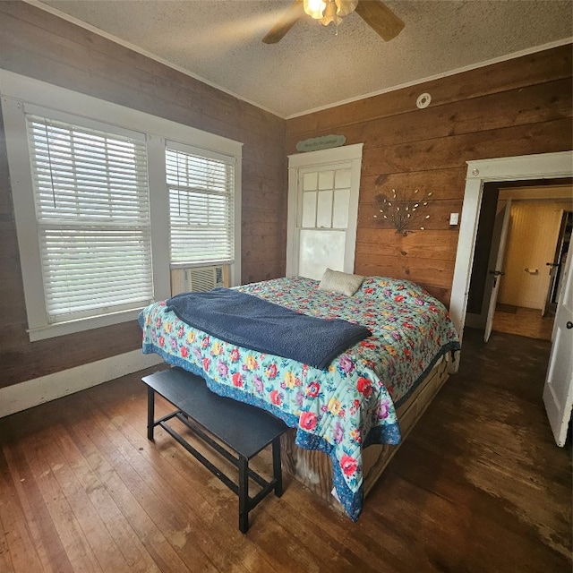 bedroom featuring wooden walls, ceiling fan, dark wood-type flooring, and a textured ceiling