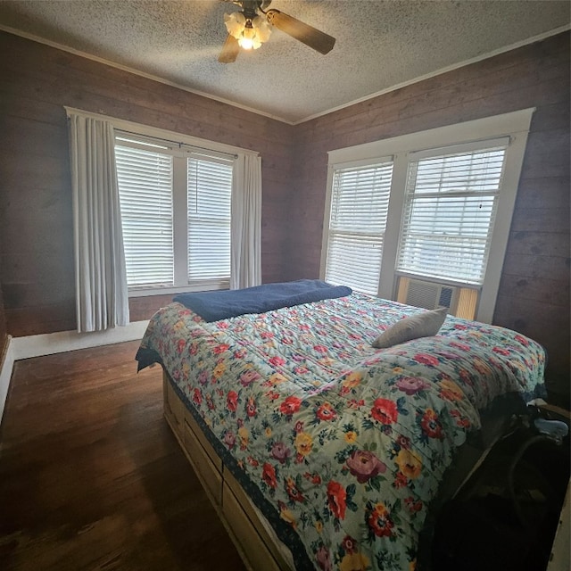 bedroom featuring ceiling fan, a textured ceiling, dark hardwood / wood-style floors, and wooden walls