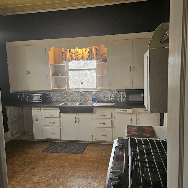 kitchen featuring white cabinets, backsplash, stove, and sink