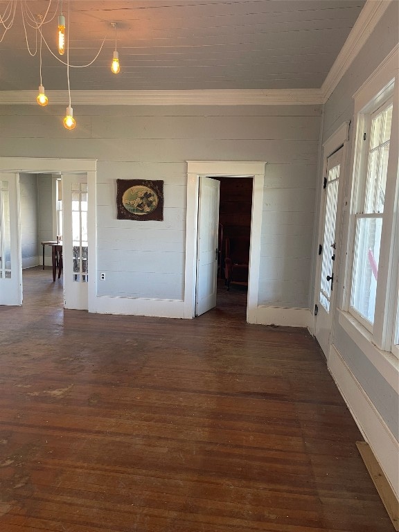 empty room with an inviting chandelier, dark hardwood / wood-style floors, and crown molding