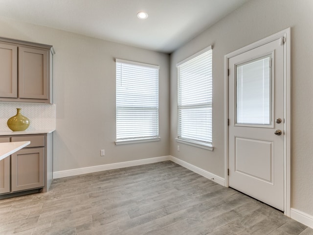 unfurnished dining area featuring light wood-type flooring and a healthy amount of sunlight