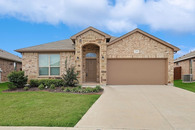 view of front of home featuring cooling unit, a garage, and a front lawn