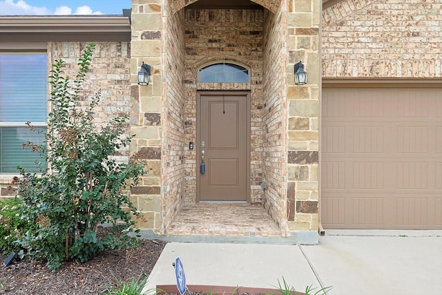 entrance to property featuring stone siding, brick siding, and an attached garage