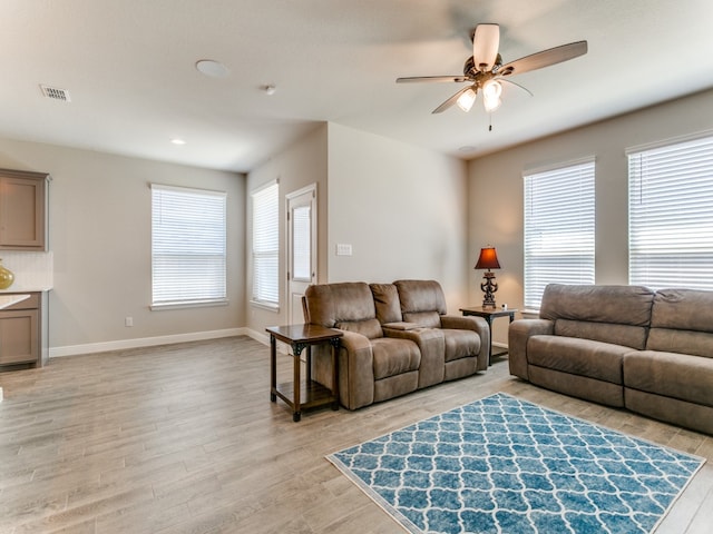 living room featuring ceiling fan, plenty of natural light, and light hardwood / wood-style floors