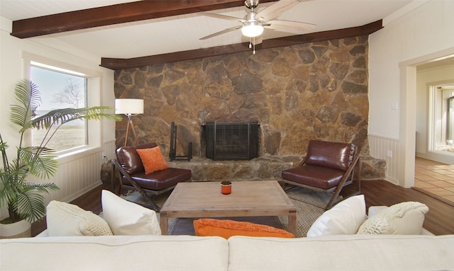 living room featuring tile flooring, beam ceiling, ceiling fan, and a stone fireplace