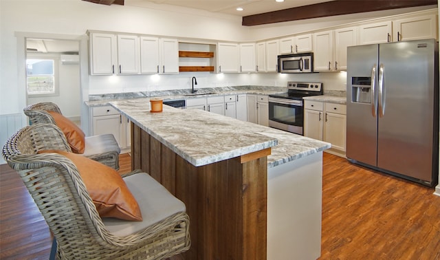 kitchen with a breakfast bar, white cabinets, dark hardwood / wood-style flooring, stainless steel appliances, and sink