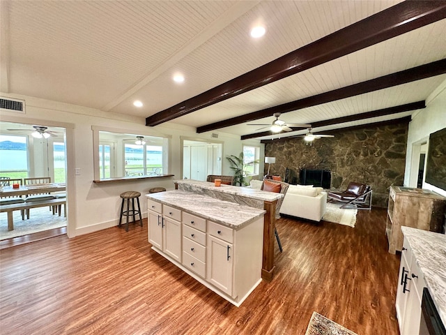 kitchen featuring wood-type flooring, a fireplace, ceiling fan, and white cabinetry