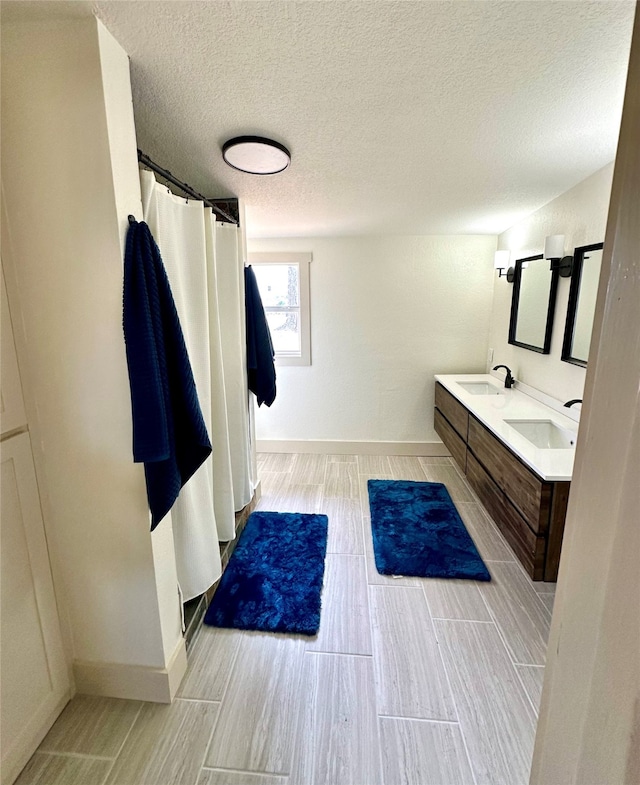 bathroom with a textured ceiling, double vanity, and tile flooring