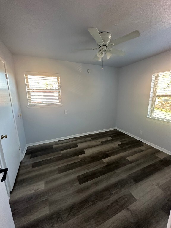 unfurnished room featuring dark wood-type flooring and ceiling fan