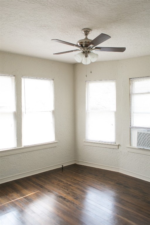 unfurnished room with a textured ceiling, dark hardwood / wood-style floors, ceiling fan, and a wealth of natural light