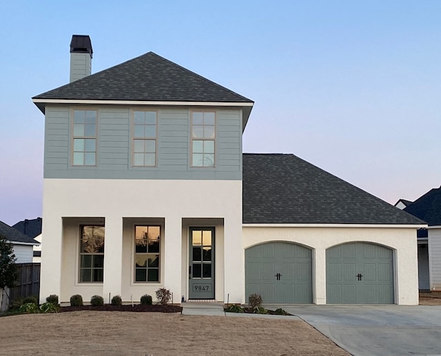 view of front of property with a shingled roof, concrete driveway, an attached garage, and stucco siding