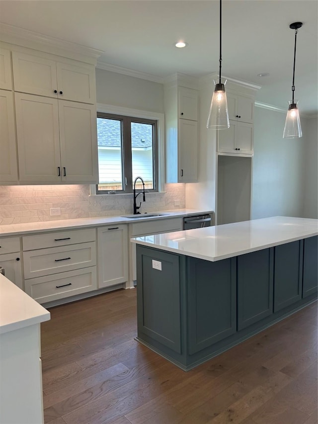 kitchen with hardwood / wood-style floors, decorative light fixtures, white cabinetry, sink, and crown molding