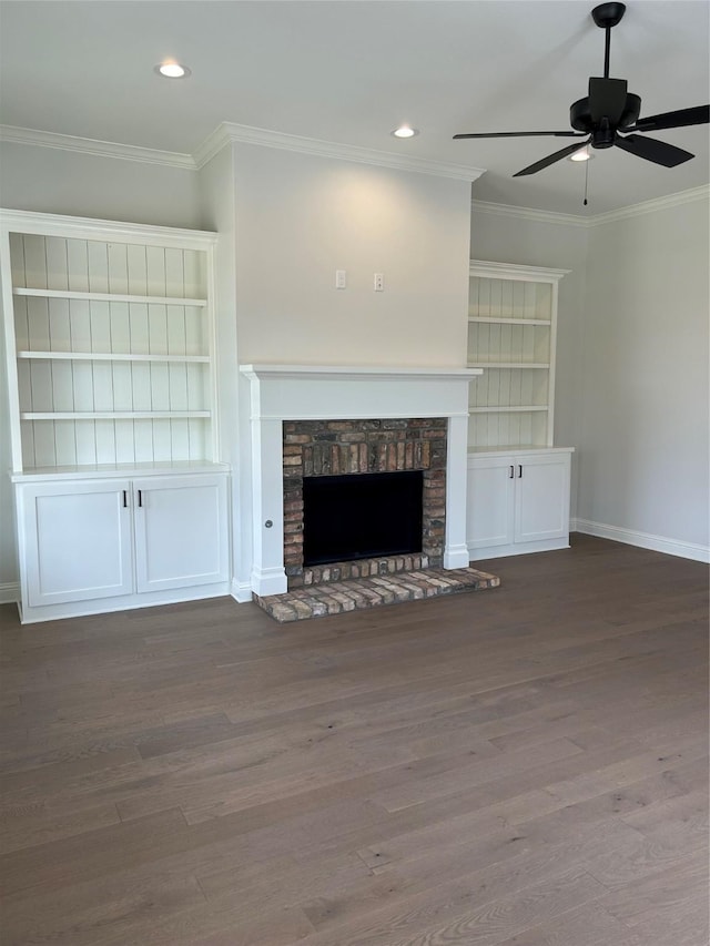 unfurnished living room featuring ceiling fan, a stone fireplace, wood finished floors, and crown molding