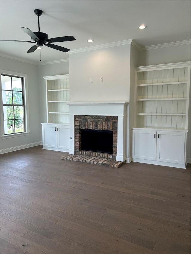 unfurnished living room featuring a stone fireplace, crown molding, dark wood finished floors, and baseboards