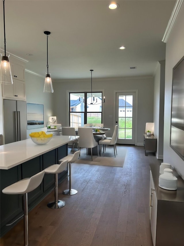 kitchen featuring hanging light fixtures, white cabinets, and stainless steel refrigerator