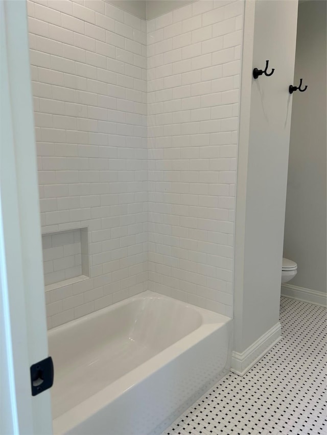 bathroom featuring washtub / shower combination, tile patterned floors, and toilet