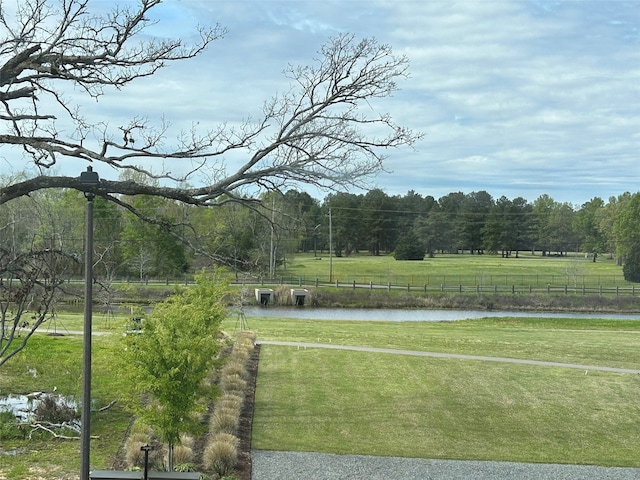 view of home's community featuring a water view, a rural view, and a lawn