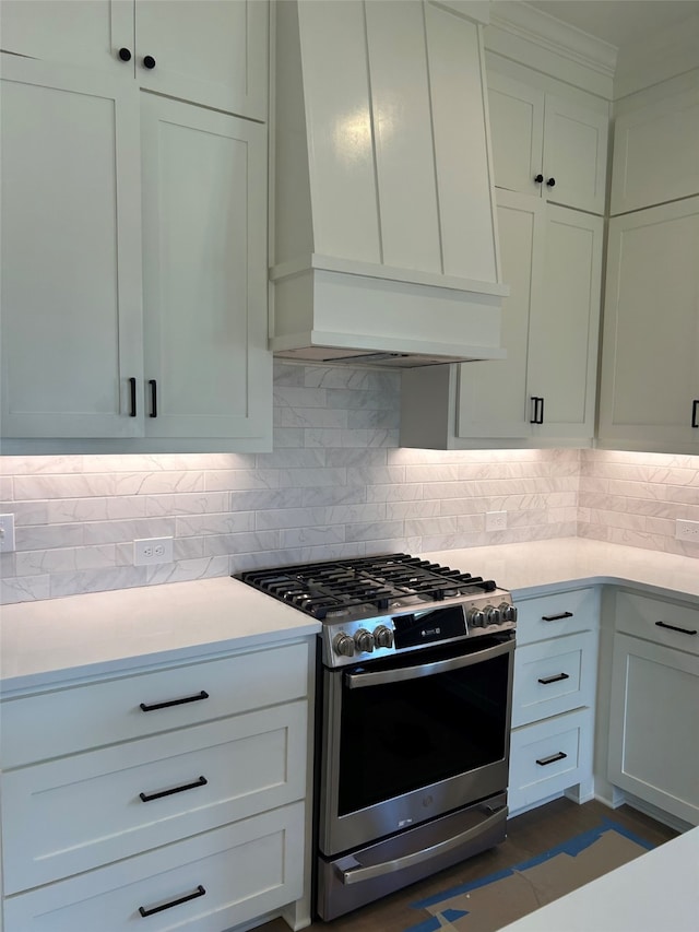 kitchen featuring tasteful backsplash, stainless steel gas range oven, premium range hood, and white cabinets