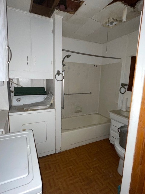 full bathroom with vanity, parquet flooring, washtub / shower combination, toilet, and washing machine and clothes dryer