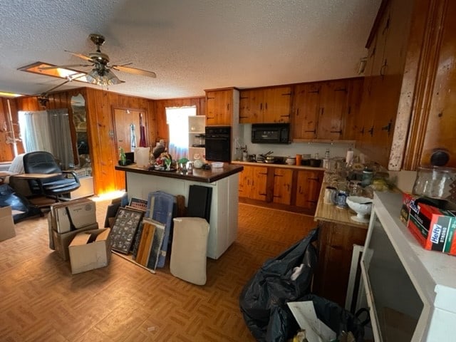 kitchen featuring a textured ceiling, ceiling fan, light parquet floors, and black appliances