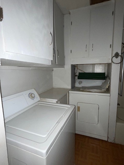 laundry room featuring dark parquet floors, cabinets, and washing machine and clothes dryer