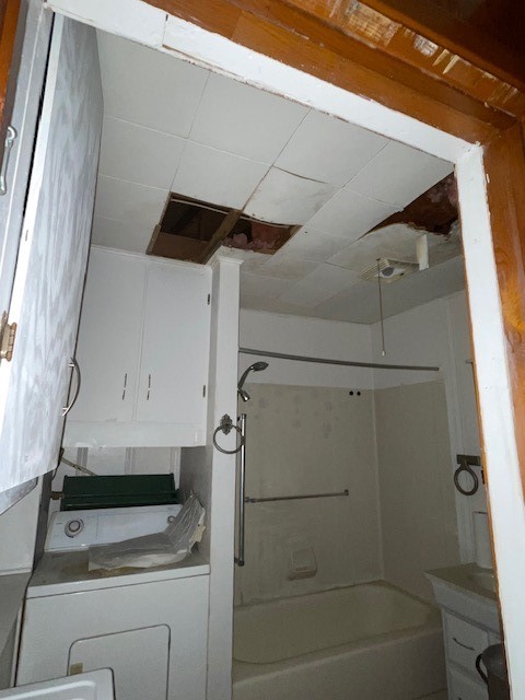 bathroom featuring vanity, shower / tub combination, and washer / clothes dryer